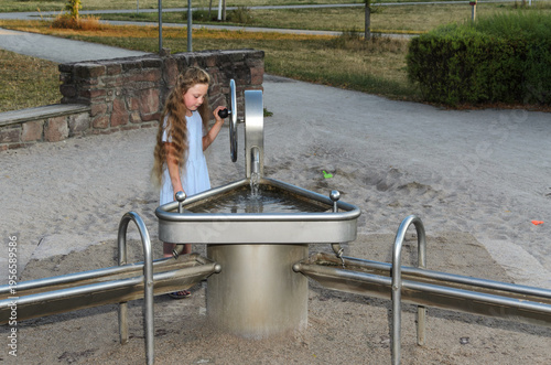 Title Little girl playing with playground water pump