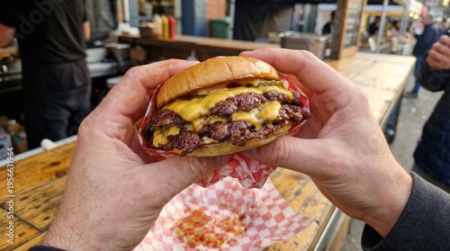 Photos Point of view of a person holding a massive double cheeseburger with melting cheese and bacon