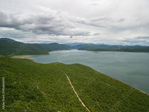 Cuadro en lienzo Bosnia and Herzegovina Vlahinja - 05 29 2025 Landscape drone photo of Bileća Lake, dense forest, rolling hills, and distant mountains in Vlahinja, Bosnia under a cloudy sky