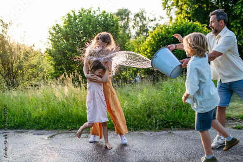 Father and son pouring water on girls during Easter Monday tradition.