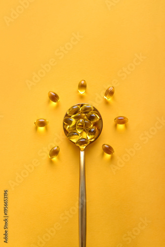 Golden spoon with soft gels vitamin D (cholecalciferol) in shape of sun