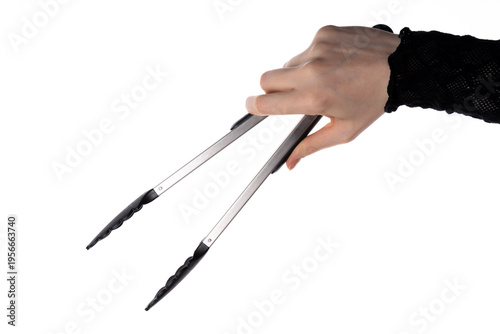 Tablou pe pânză Female hand holding metal kitchen tongs with black silicone tips, isolated on white background, studio closeup of cooking utensil