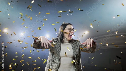 Businesswoman celebrating victory with arms wide open as golden confetti falls around her, representing business success, professional achievement, and the fulfillment of career goals. The vibrant