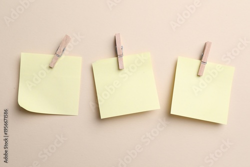 Reminder. Sticky notes with clothespins on beige background, top view