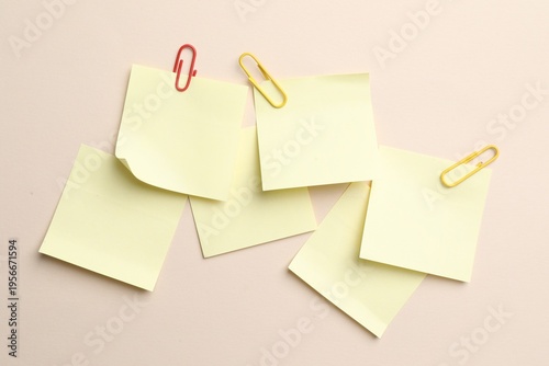 Reminder. Sticky notes with paperclips on beige background, top view
