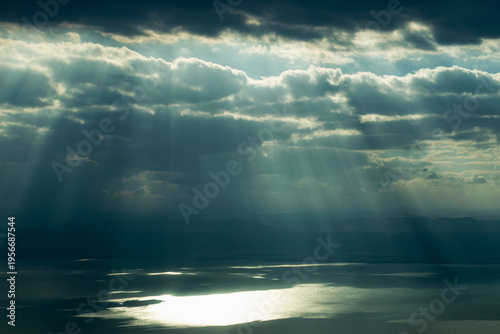 Картината върху платно Dramatic sunbeams breaking through dark storm clouds over the Dead Sea in Jordan