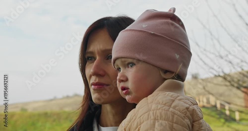 Young mother holding child in arms outdoors, close family connection and everyday motherhood in natural environment