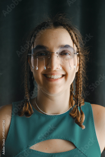 Portrait of cheerful young woman with braids wearing creative cloud shaped eyewear with hanging crystals, representing optimism, individuality and unique modern fashion style.