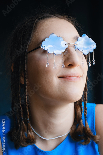 Close-up portrait of woman in unique cloud-shaped sunglasses with rain-like crystals. Creative, surreal concept for fashion, beauty, art, or weather themes.