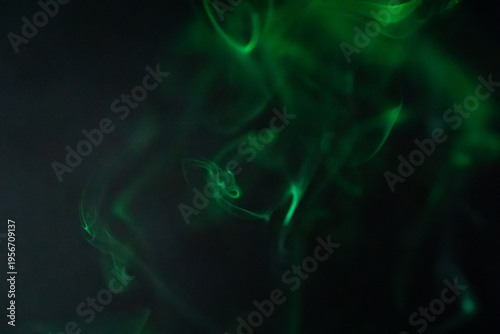 Schilderij op canvas Green smoke swirls gracefully against a dark background creating a mystical atmo