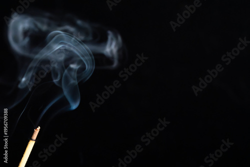Tableau sur toile An incense stick emits gentle wisps of smoke against a dark background