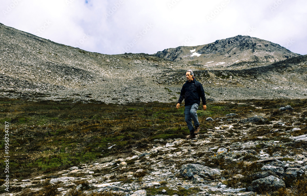 Fototapeta premium Traveler hiking and returning through the rocky slopes of Cerro del Medio back to Ushuaia city