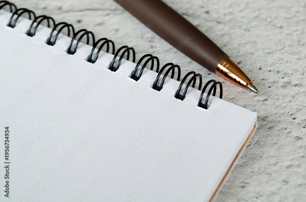 Obraz premium Clean white spiral notebook on textured surface with pencil at top edge, with customizable space on notebook for text or ideas