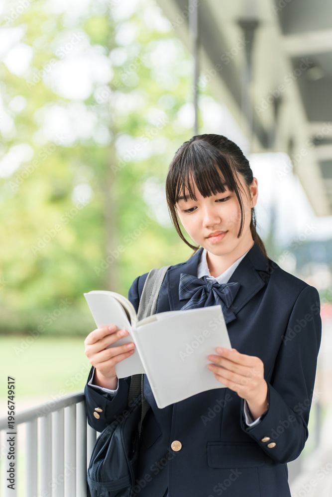 Fototapeta premium Female high school students, middle school students, and high school students who are preparing for entrance exams read reference books, textbooks, and workbooks on their way to school.