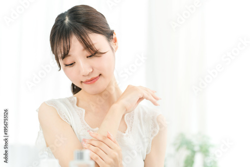 Free Download A young Asian woman applying body lotion and body cream to her arm. - GFXLoad