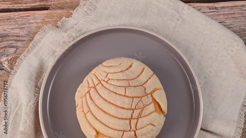 Authentic Mexican sweet bread bun (concha) on a wooden table with linen napkin