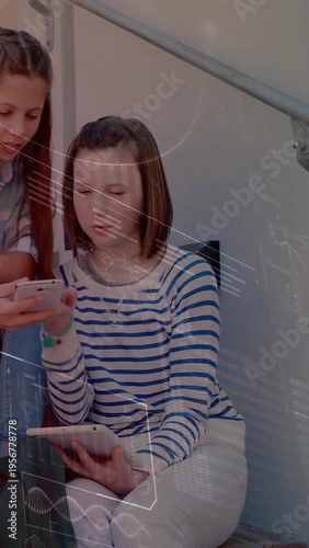 Vertical video: Seated teen holding tab friend showing phone tapping sharing tech AR UI over them