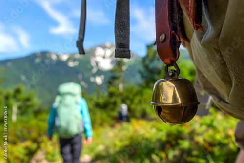 登山における熊対策、バックパックに付けたベアベル（熊よけの鈴）と山道を歩く登山者のボカした風景。安全管理とレジャー
