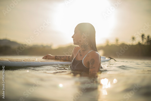Candid lifestyle photo of a surfer woman at sunrise