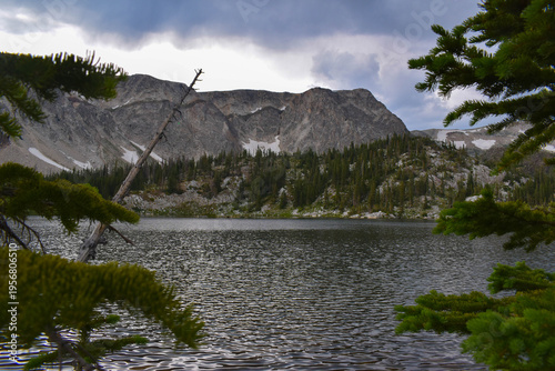 Vista of a lake in front of the mountains and forest from Medicine Bow-Routt National Forest in Wyoming, USA