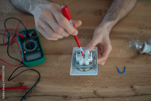 Electrician hands testing electrical outlet using tester
