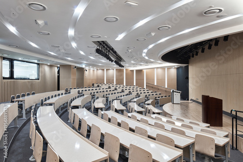 Large tiered lecture hall with wood panel walls in academic facility