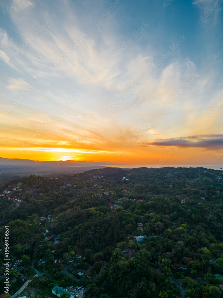 Obraz premium Panoramic aerial vertical shot of the mountainous area full of vegetation with a sunrise in Quepos in the Puntarenas Province of Costa Rica