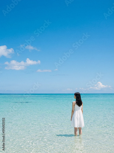 Authentic young woman standing in the pristine ocean water under a blue sky