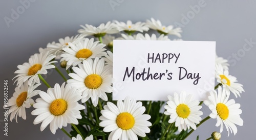 A bouquet of white daisies with a happy mothers day card on a gray background