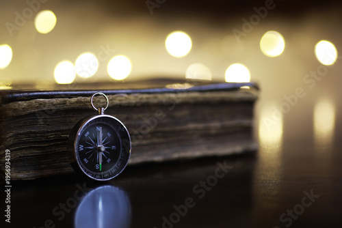 Vintage Compass on Antique Book with Warm Bokeh Lights Background - Exploration and Navigation Concept