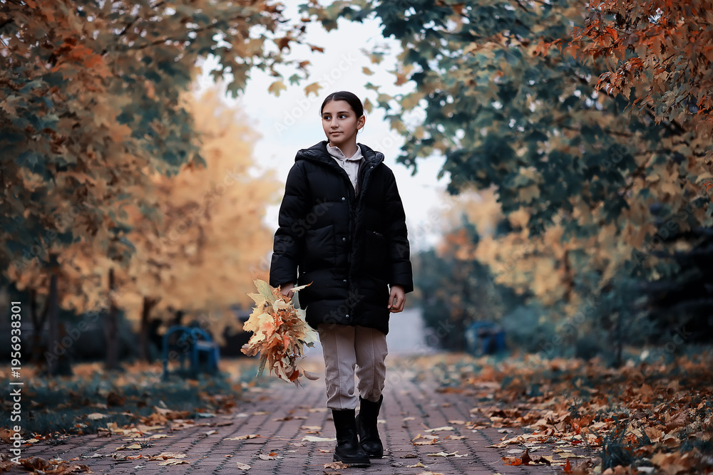 Fototapeta premium Woman Walking Through Autumn Park Holding Leaves, Enjoying Nature