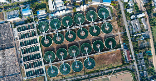 Wastewater treatment plant aerial view, circular tanks and large reservoirs in industrial facility, environmental engineering and sustainability concept, wide angle with natural lighting.