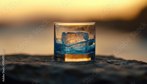 A glass with a large , filled with blue liquid, on a rock. A sunset background. AI.