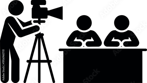 A camera operator filming two people seated at a desk during an interview.