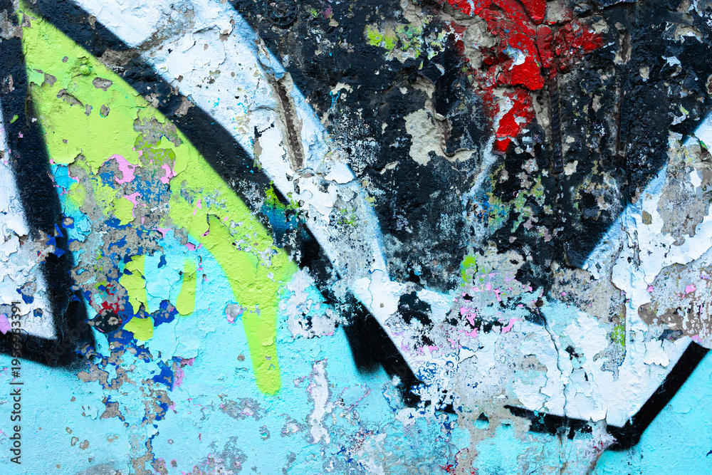 Fototapeta premium Weathered concrete wall with distressed blue peeling paint and spray paint fragments. Aged urban surface with substrate texture and paint erosion for street art backgrounds and grunge designs.
