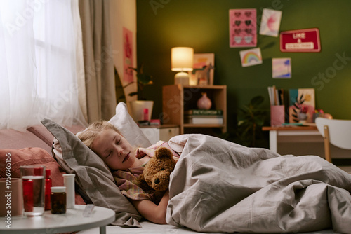 Obraz na plátně Caucasian child girl sleeping in bed hugging toy bear, resting in cozy bedroom w