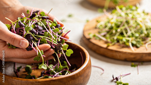 Hands holding microgreens with wooden bowls in a kitchen setting for food preparation