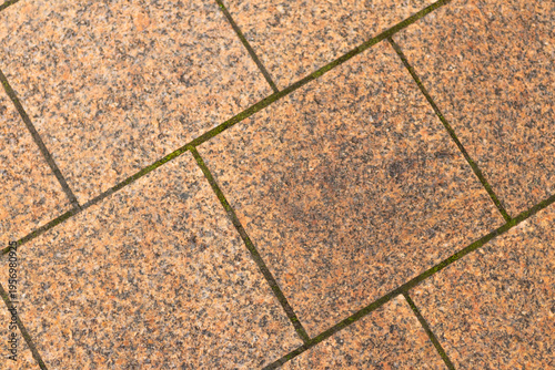 Granite tiles cover a walkway with even pieces arranged in a grid pattern during daylight hours