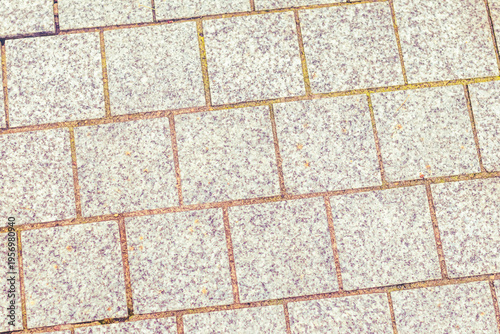 Granite tiles cover a walkway with even pieces arranged in a grid pattern during daylight hours