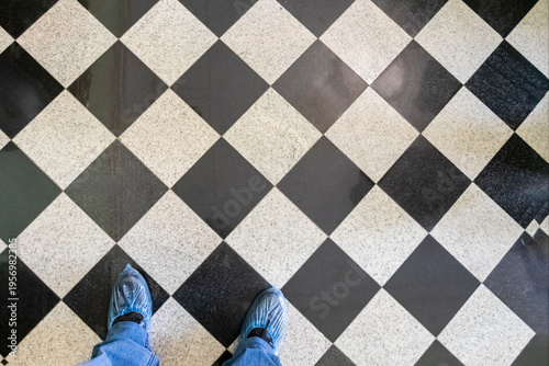 Person standing on checkered floor with blue shoes in indoor space during daylight