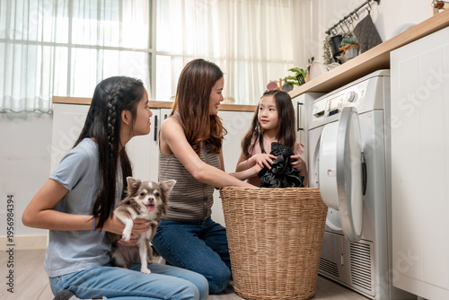 Asian beautiful mother teaching young daughters doing laundry at home. 