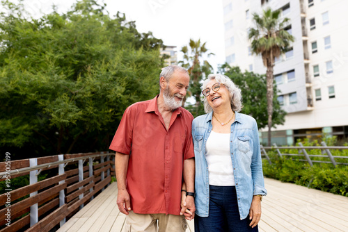 Senior couple holding hands laughing walking outdoors