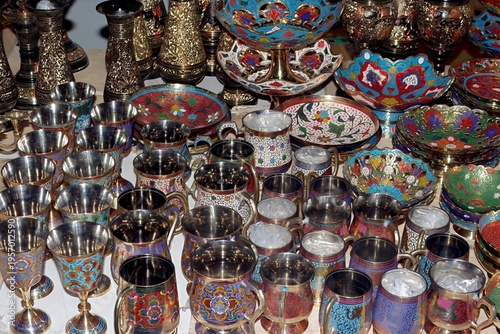 Indian brass and enamel cups, bowls, and vases with vibrant colors and elaborate floral patterns