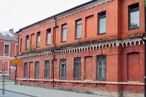 Red brick building with white decorative elements and multiple windows lines a quiet urban street, showcasing classic architectural design.