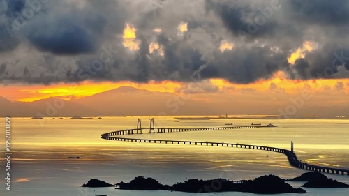 Scenic aerial view of Hong Kong-Zhuhai-Macao Bridge spanning across sea at sunset with dramatic golden sky and clouds in China.