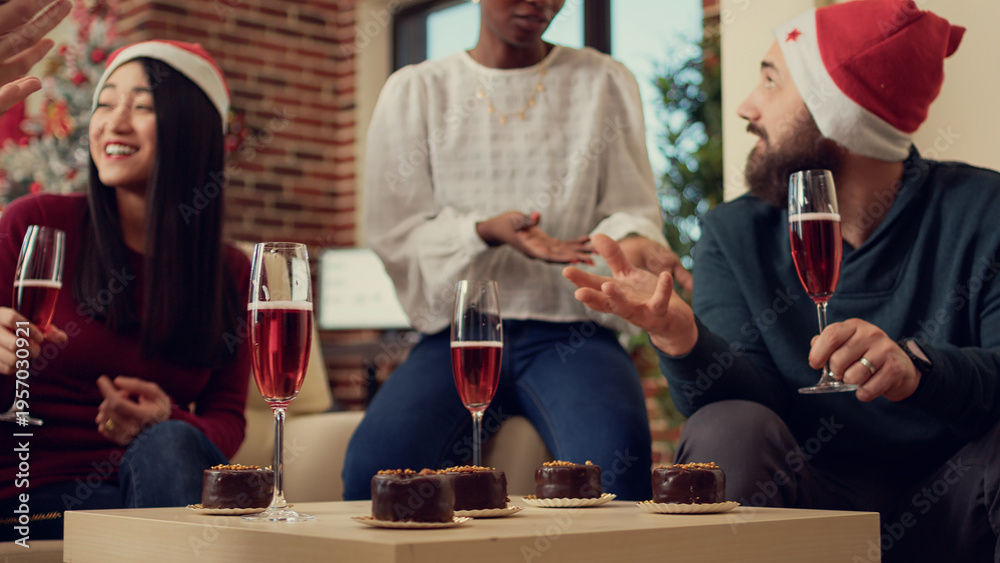 Obraz premium Diverse people drinking glasses of wine at holiday festivity in office with xmas decorations. Serving alcoholic beverage to celebrate christmas eve party with presents and festive decorations.