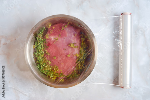 Marinated pork shoulder is covered with cling film