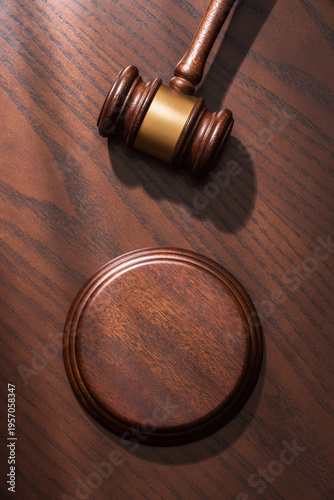 Quadro su tela Close-up of a judge’s gavel with sound block against a polished dark brown wood background in soft sunlight, symbolizing justice and legal authority in a courtroom setting