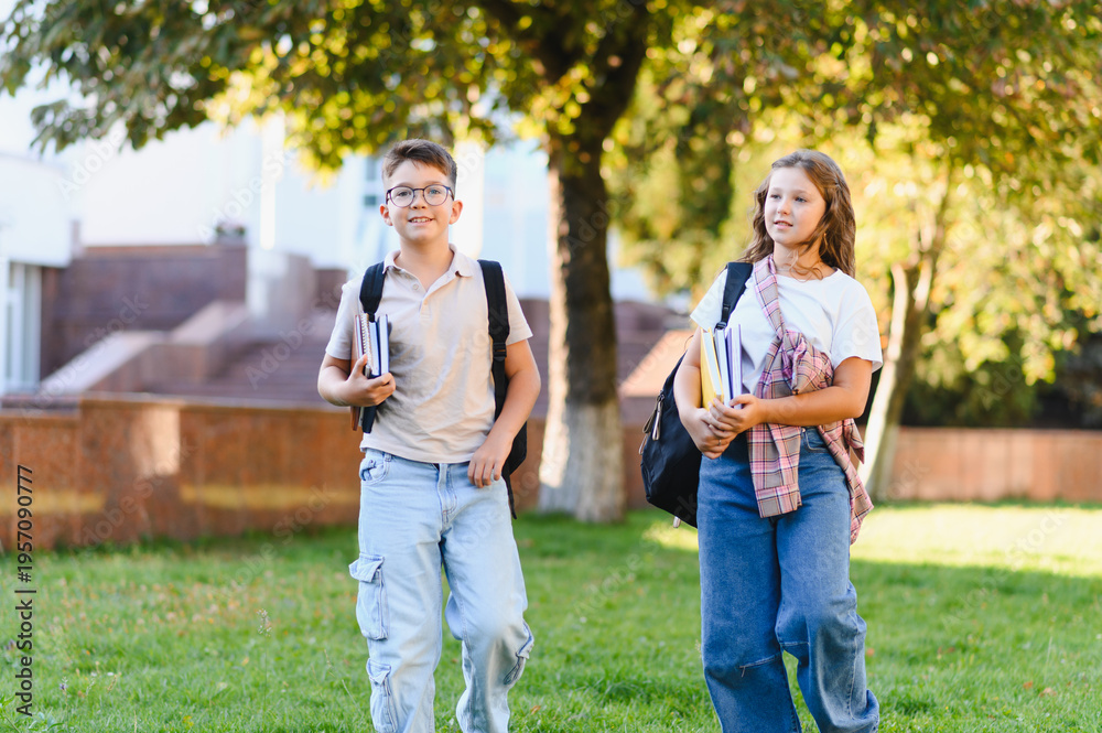 Obraz premium Schoolchildren walking on campus with backpacks and books