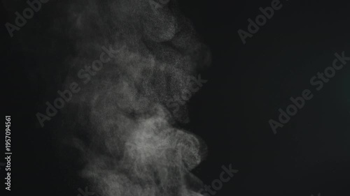Slow motion steam rising from boiling water over black background